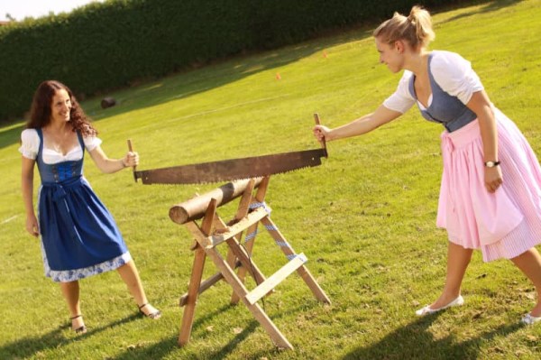 Zwei Frauen bei einer Team-Challenge, die gemeinsam ein Stück Holz absägen